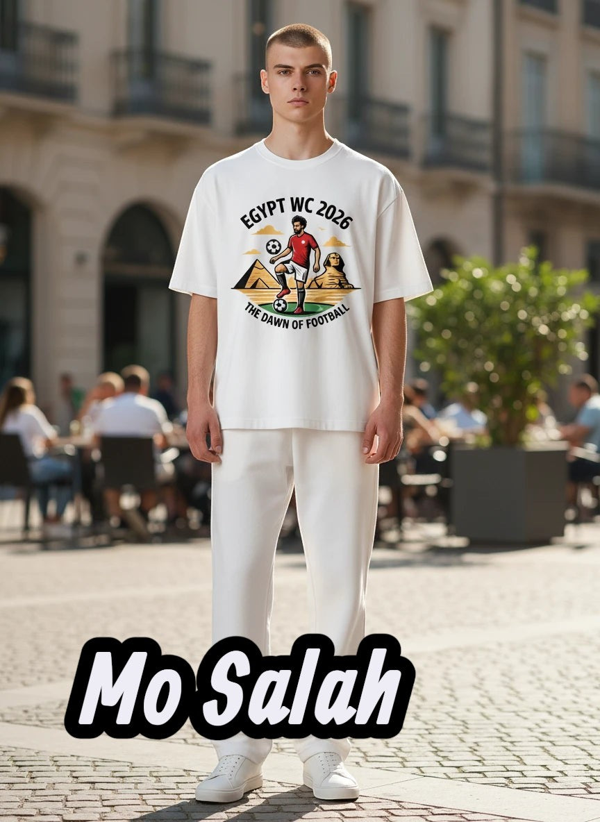 Coptic Mary Shop white cotton t-shirt with Egypt WC 2026 graphic featuring a footballer, pyramids, and Sphinx.